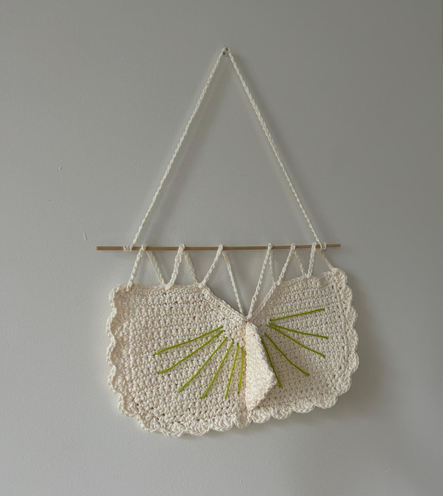 A sundial woven from yarn, hanging on a wall